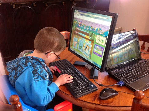 child with significant vision impairment plays on a computerusing a qwerty keyboard.