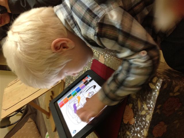 child with significant vision impairment colouring in a picture on an ipad.