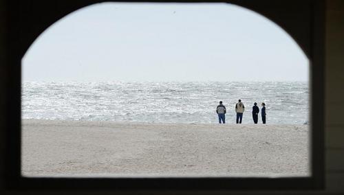 people are framed through a window as they looks out to the atlantic ocean as the town prepares for hurricane sandy oct 27, 2012 in cape may, new jersey. -- photo: afp 