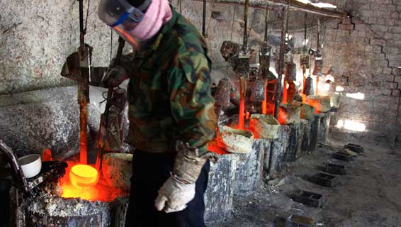 a worker at the a smelting workshop prepares to pour the rare earth metal lanthanum in to a mould