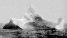 black and white photograph of a large iceberg with three 