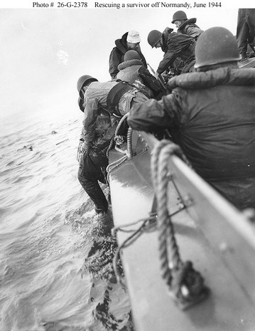 a survivor is pulled aboard a coast guard boat after his ship was hit during the normandy landings