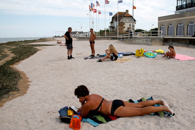 a tourist sunbathes on a former juno beach landing area where canadian troops came ashore on d-day at bernieres sur mer, france