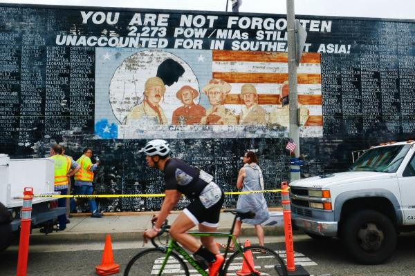 this may 30, 2016 file photo shows a biker rides past a vietnam war memorial mural as a metropolitan transit authority workers prepare to cover the vandalized memorial in the venice area of los angeles. (ap photo/richard