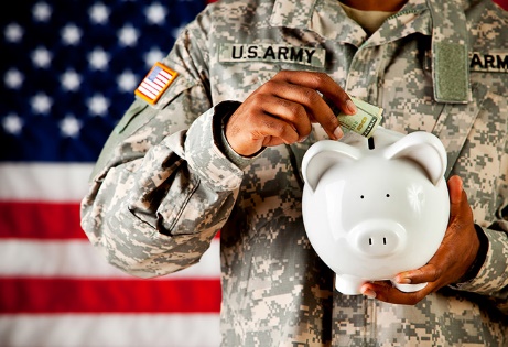 image of army person in uniform placing money into a piggy bank.