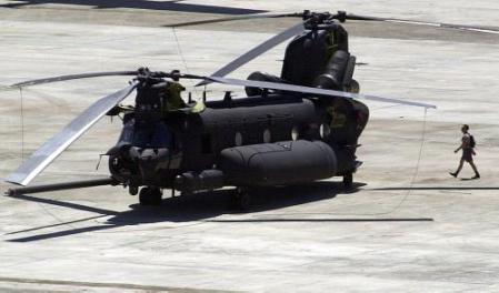 a member of the mactan air force base ground crew walks behind one the two remaining mh-47e chinook helicopters.