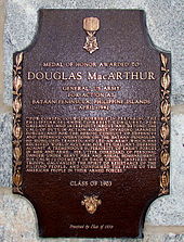 a bronze plaque with an image of the medal of honor, inscribed with macarthur\'s medal of honor citation. it reads: 