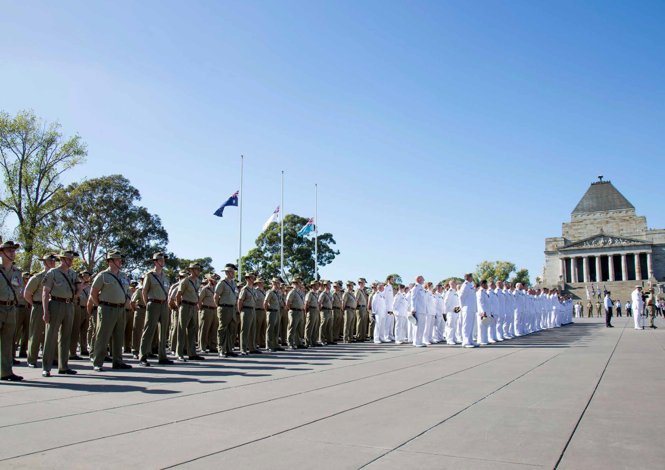 soldiers in formation in front of the shrine of rememberance. flags are at half mast.