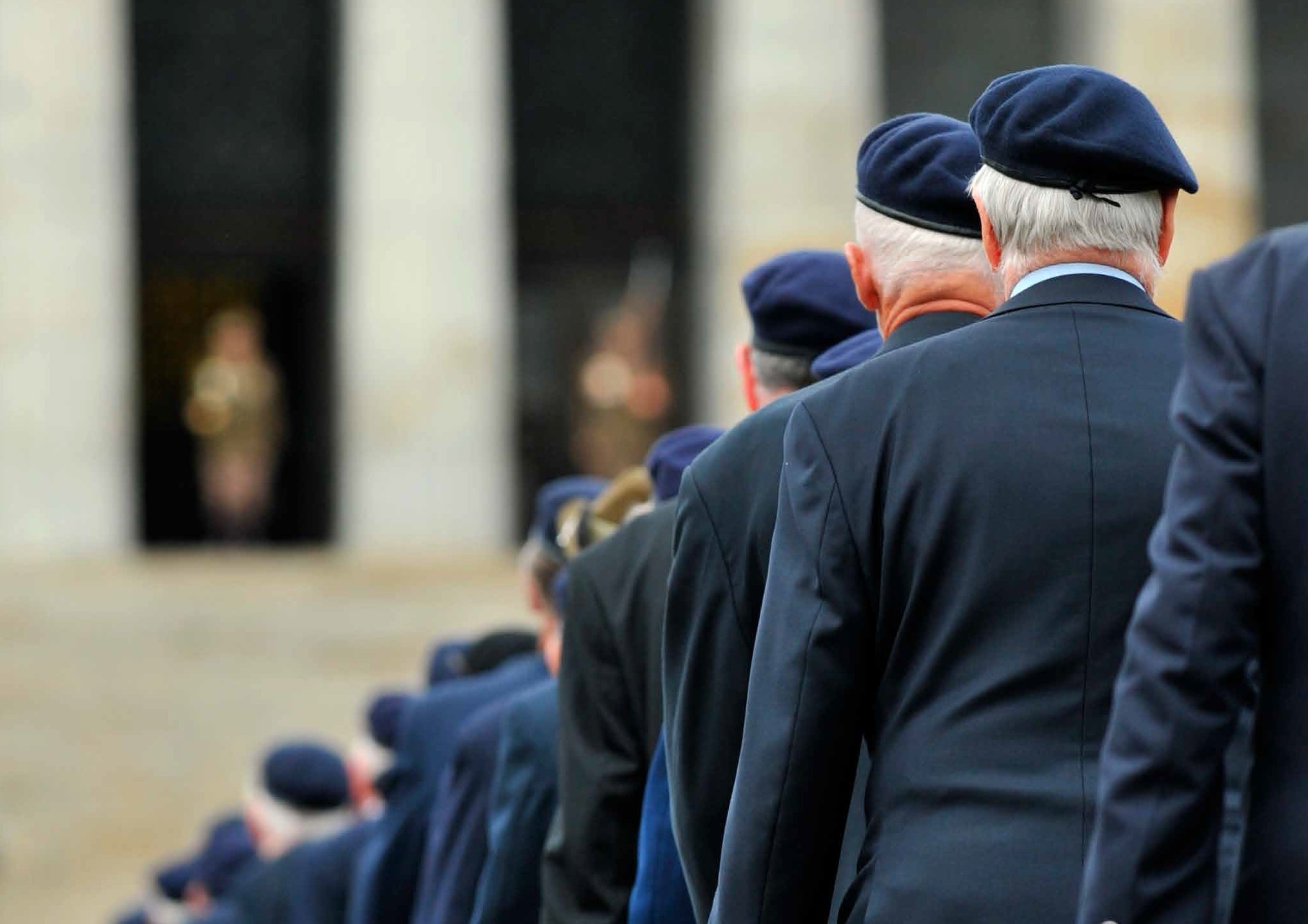 veterans standing in formation looking towards the shrine of rememberance